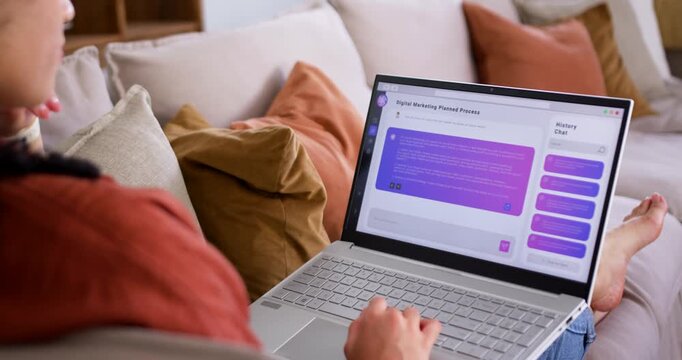Woman on left sofa reading purple chat bubble and typing on silver laptop, leaning, copy space