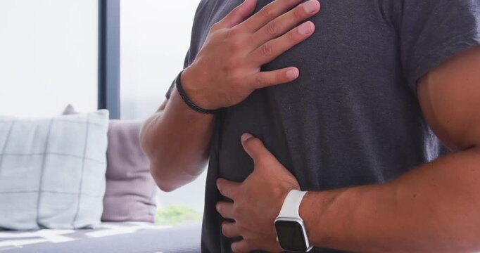 Man placing hands on chest and belly, checking heartbeat and breathing with smartwatch at home