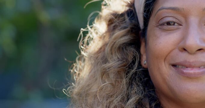 Indian and African woman smiling then laughing in garden with headband, backlit curls, copy space