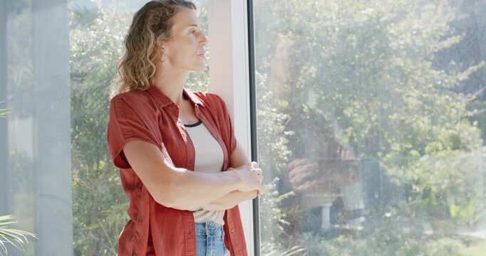 Female standing by glass panel, noticing camera reflection, turning toward camera and smiling