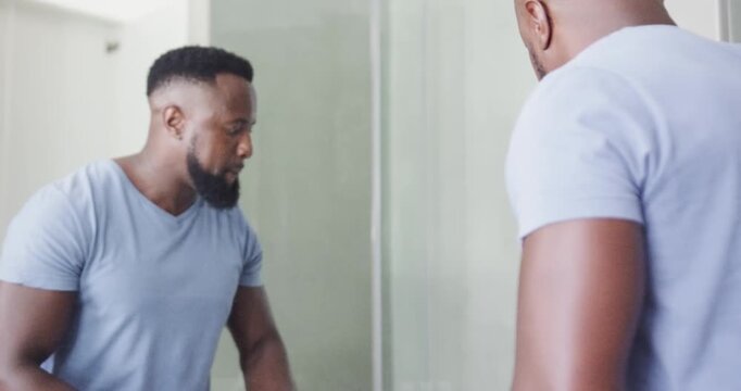 Man starting AM grooming at sink, brushing with toothbrush, rinsing, checking mirror, smiling
