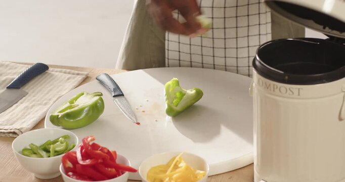 African American man placing half green pepper on counter coring into compost pail slicing to cook