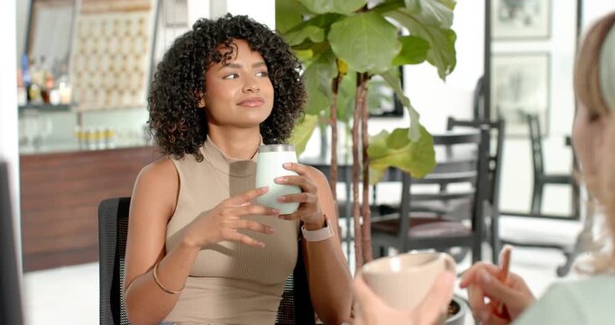 Diverse female staff, peer offering cup and spoon, woman sipping mint tumbler during friendly chat
