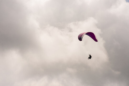 Parapente en el cielo con vela morada sobre nubes dram&aacute;ticas