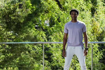 African American man standing on balcony in tee sweats touching railing wristwatch, copy space © wavebreak3