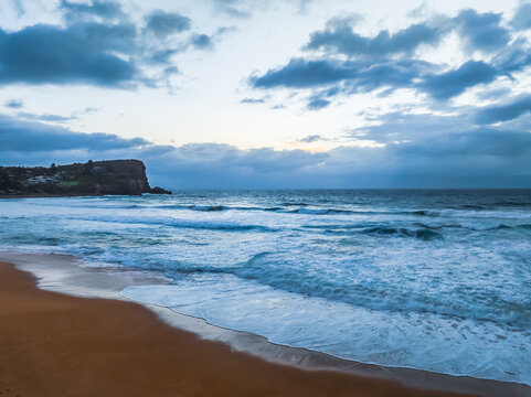 Seaside Sunrise with rolling waves and rain clouds