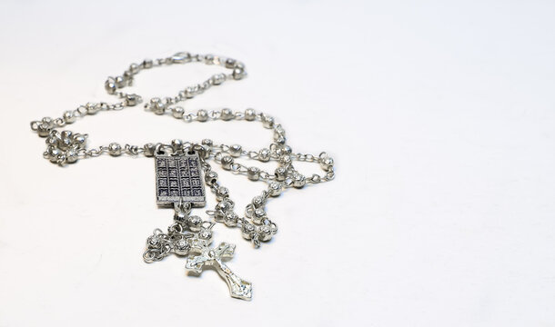Catholic rosary beads with silver crucifix and scapular medal isolated on a white background.