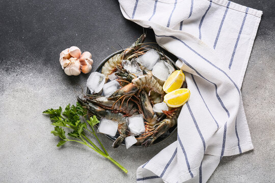 Plate with fresh raw shrimps, lemon and parsley on grunge background