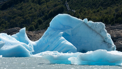 Floating blue icebergs in cold glacial water, natural polar landscape with frozen ice formations and calm surface © Daryna