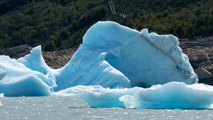 Floating blue icebergs in cold glacial water, natural polar landscape with frozen ice formations and calm surface © Daryna