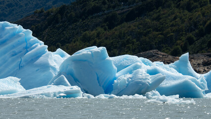 Floating blue icebergs in cold glacial water, natural polar landscape with frozen ice formations and calm surface © Daryna