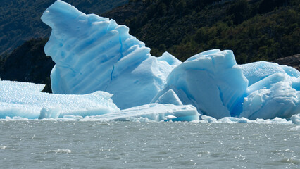 Floating blue icebergs in cold glacial water, natural polar landscape with frozen ice formations and calm surface © Daryna