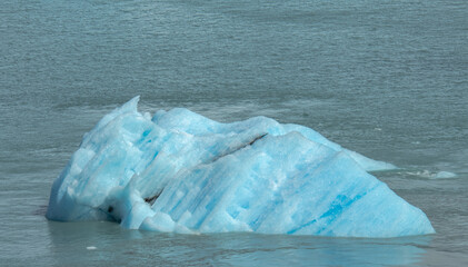 Floating blue icebergs in cold glacial water, natural polar landscape with frozen ice formations and calm surface © Daryna