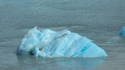 Floating blue icebergs in cold glacial water, natural polar landscape with frozen ice formations and calm surface © Daryna