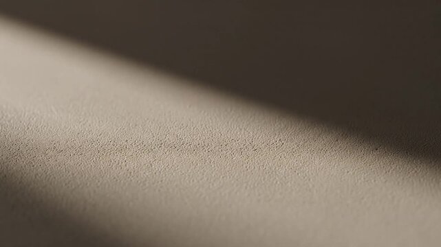 Soft textured background with a diagonal shadow creating a minimalist abstract composition with warm tones