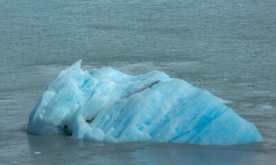 Floating blue icebergs in cold glacial water, natural polar landscape with frozen ice formations and calm surface © Daryna