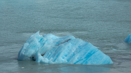 Floating blue icebergs in cold glacial water, natural polar landscape with frozen ice formations and calm surface © Daryna