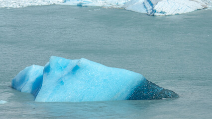 Floating blue icebergs in cold glacial water, natural polar landscape with frozen ice formations and calm surface © Daryna