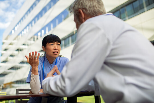 Nurse and doctor discussing patient care outside hospital