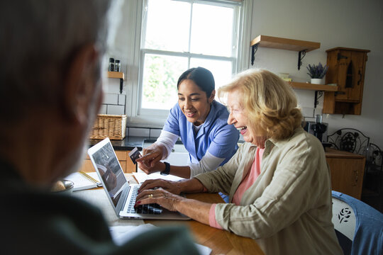 Caregiver helps senior woman with online banking at home