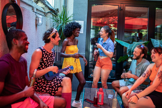 Friends laughing and playing music at a summer patio party