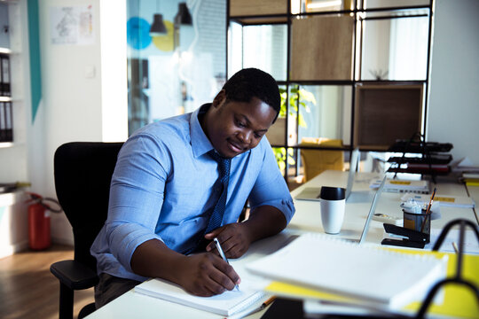 Businessman writing notes at modern office desk