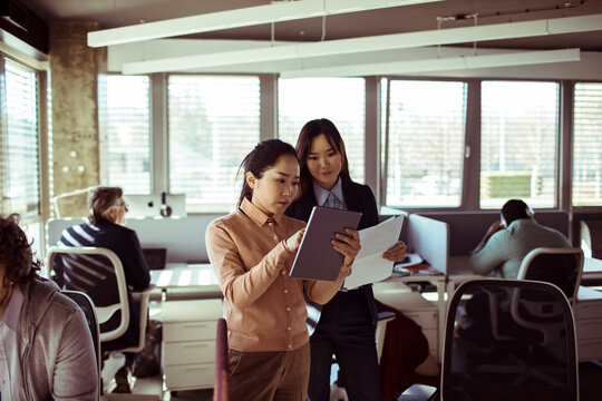 Businesswomen collaborating on tablet in modern office