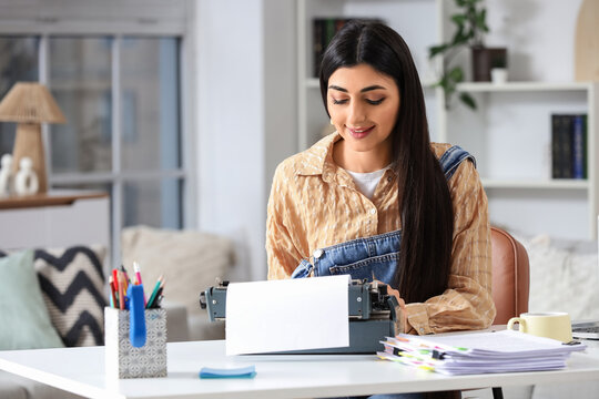 Female screenwriter using vintage typewriter at table in office