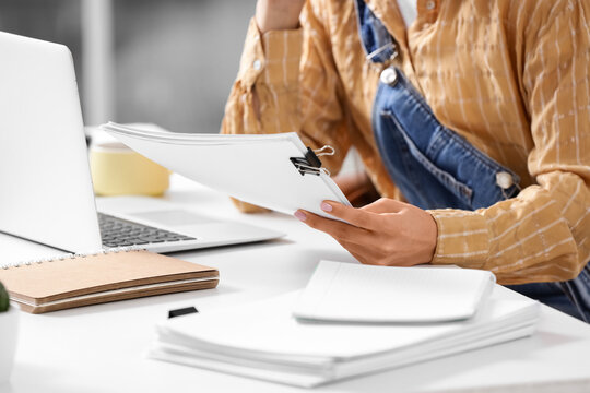 Female screenwriter with script at table in office, closeup