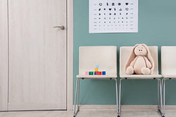 Obraz na płótnie Canvas Toy bunny with cubes on chairs in pediatrician's hall
