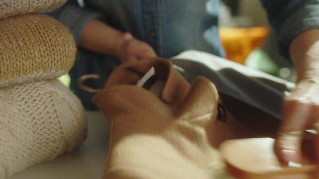 Hands use a wooden clothes brush to clean a light brown wool coat, removing lint and dust as part of a seasonal clothing maintenance routine.