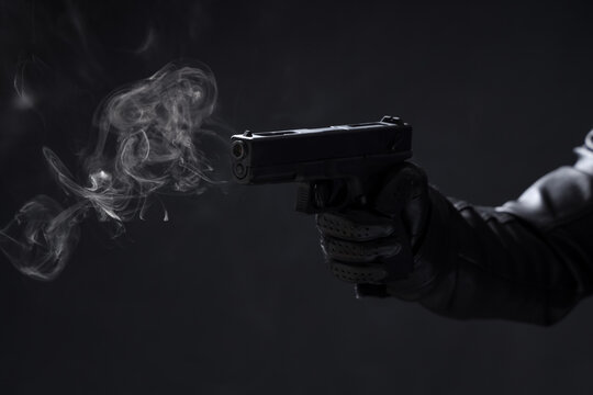 Male hand with smoking gun on black background