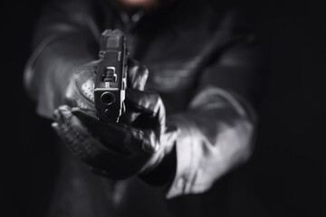 Naklejka premium Man with gun aiming at viewer on black background, closeup