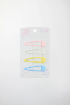 Soft colors pastel hair clips on card with floral design include pink, white, yellow, and blue. Clean background highlights product simplicity, decorative retail packaging isolated on white background