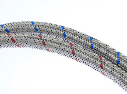 Metallic braided hose with red and blue markers. Coil rests against clean white background. Industrial or mechanical applications highlighted. Precise, professional design appeals to technical buyers.