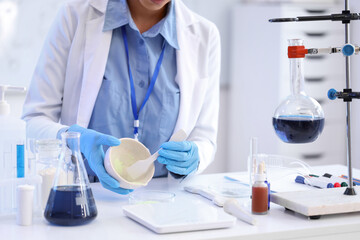 Fototapeta premium Young African-American female chemist with mortar and Petri dish working in lab, closeup