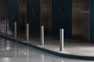 Clean, contemporary elevator area with chrome bollards and reflective flooring © Rattanachat