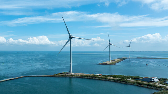 Wind Turbines in Coastal Waters of the Netherlands Generating Renewable Energy Under Blue Sky With Clouds