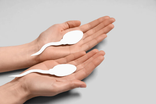 Hands with sperm cell on grey background