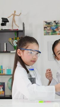 Young Asian Girl Conducting Bernoulli's Principle Science Experiment with Ping Pong Ball