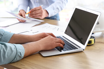 Obraz premium Male constructor working with blank laptop at table in office, closeup