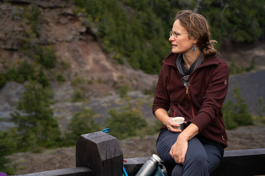 Joven mujer excursionista tomando caf&eacute; durante una caminata.