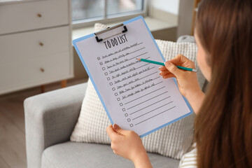 Fototapeta premium Young woman making to-do list at home, closeup