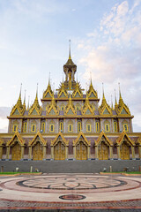The golden castle temple stands centered above the wide forecourt. Soft evening clouds spread across the open sky. © Surachetsh