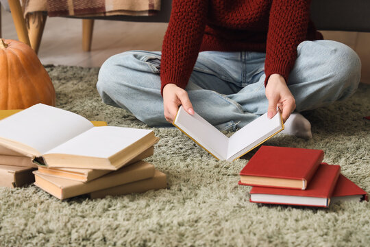 Woman with books sitting on carpet at home