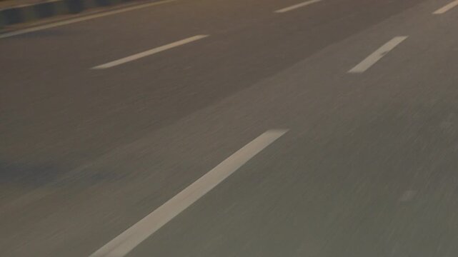 A broken line of white road markings. Close-up in motion.