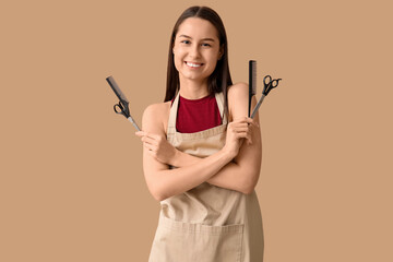 Fototapeta premium Female hairdresser with scissors and combs on brown background