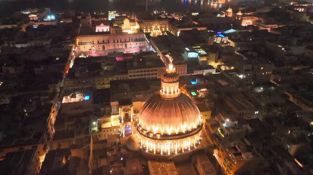 Malta drone aerial of Glowing Dome Of Illuminated Basilica of Our Lady of Mount Carmel in Valletta at Night, revealing panoramic cityscape