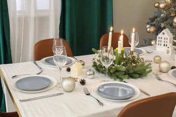 Fototapeta premium Festive table setting with burning candles and Christmas decorations in elegant dining room