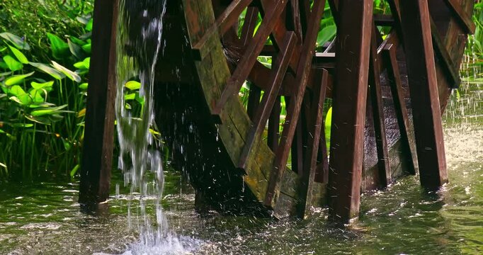 Close-up of a traditional wooden waterwheel operating in a garden pond.